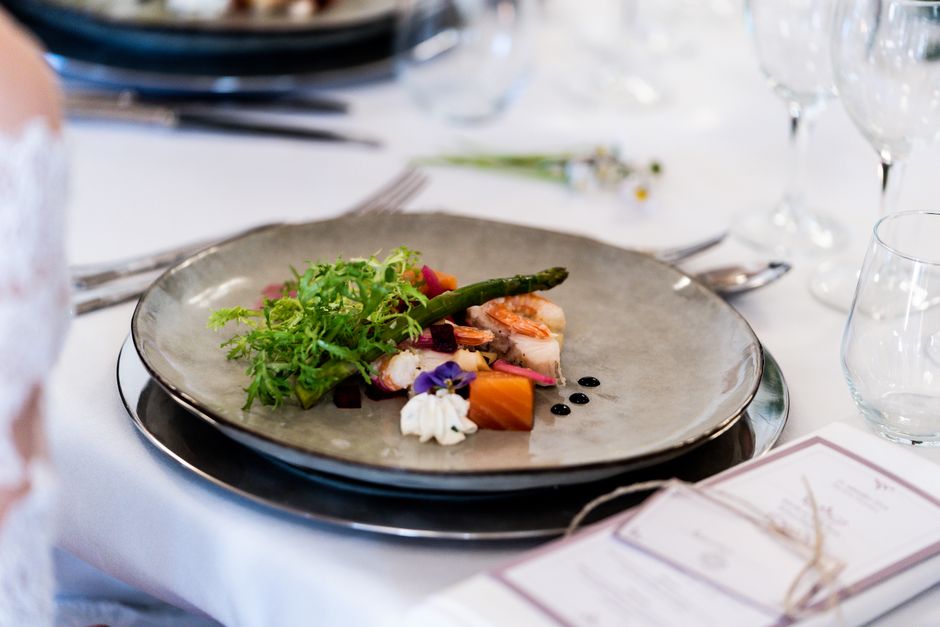 A gourmet dish with vegetables and sauce elegantly presented at a sophisticated table setting.